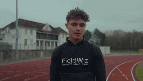 a man wearing a fieldwiz shirt stands in front of a building