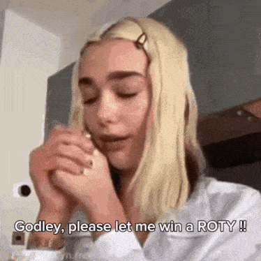 a woman with blonde hair is praying with her hands folded and says godley please let me win a roty .