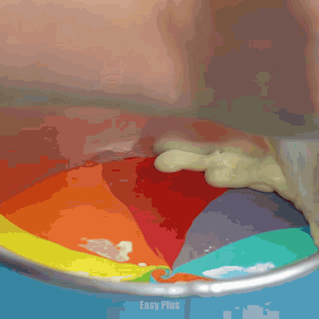 a person is pouring rainbow colored liquid into a bowl with easy plus written on the bottom
