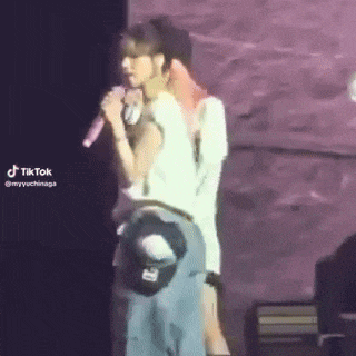 a man and a woman are standing next to each other on a stage . the woman is holding a microphone .