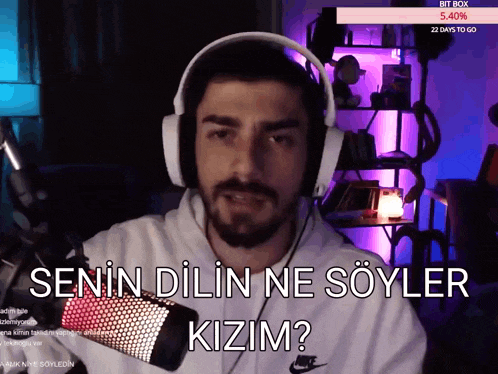 a man wearing headphones is talking into a microphone with the words " senin dilin ne söyler kizim " on the screen