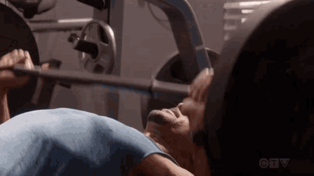 a man is lifting a barbell in a gym .