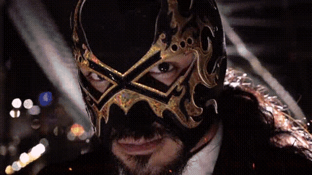 a man with a beard is wearing a black and gold mask with a crown on it .