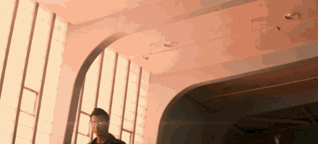 a man is walking down a set of stairs in a room with a lot of windows