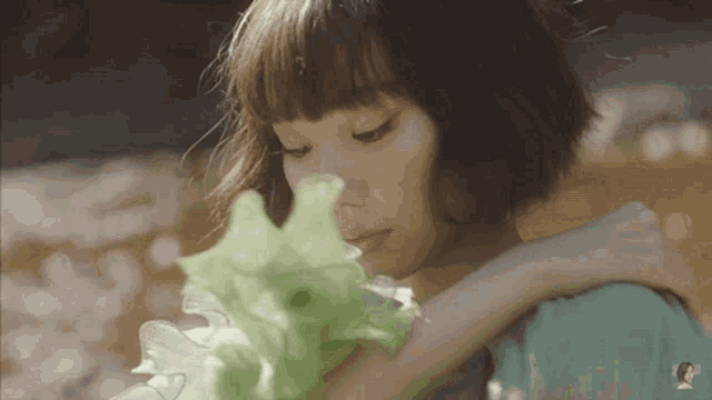 a woman with short hair is holding a green flower in her hand