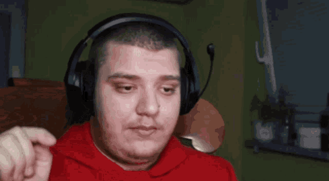 a man wearing headphones and a red shirt is making a funny face