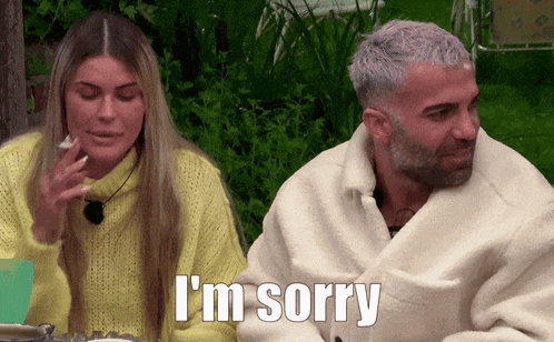a man wrapped in a blanket says i 'm sorry while sitting next to a woman