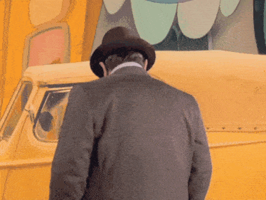 a man in a hat stands in front of a yellow van