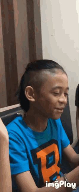a young boy wearing a blue shirt with the letter p on it