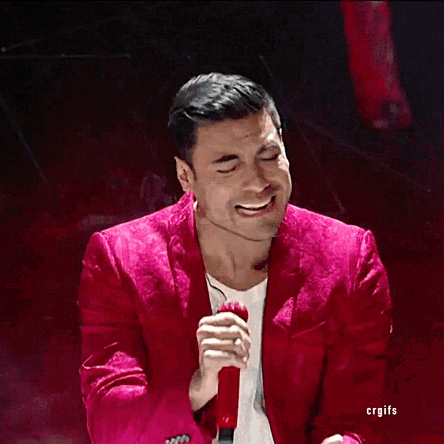 a man in a red jacket sings into a microphone