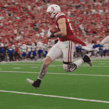 a football player wearing a helmet with the letter n on it is running with the ball