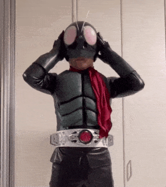 a man in a superhero costume is adjusting his mask