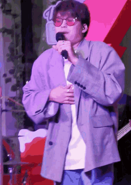 a man singing into a microphone while wearing sunglasses and a jacket