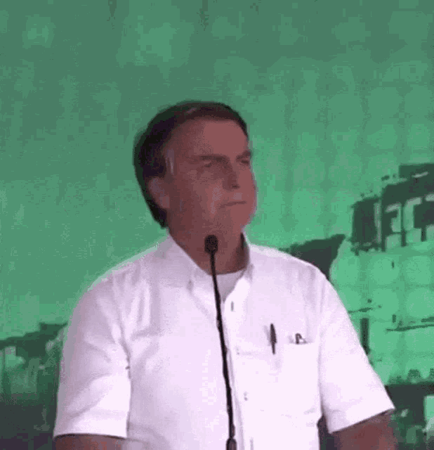 a man in a white shirt is standing in front of a microphone and making a funny face .