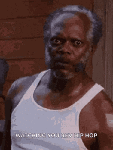 a man with a beard is wearing a white tank top .