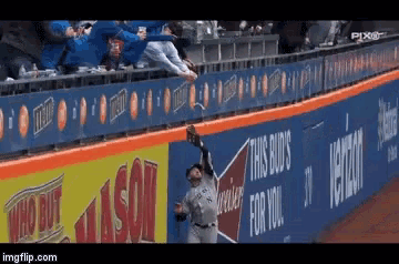 a baseball player reaches for a ball in front of a banner that says this bud 's for you
