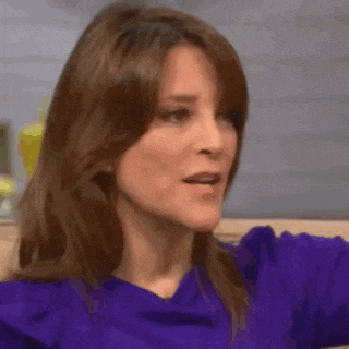 a woman in a purple shirt is making a funny face while sitting on a couch .