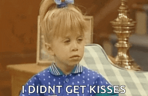 a little girl in a blue shirt is sitting on a chair and says `` i did n't get kisses '' .