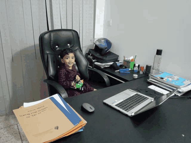 a little girl sits at a desk with a laptop and a book that says ' a few letters ' on it
