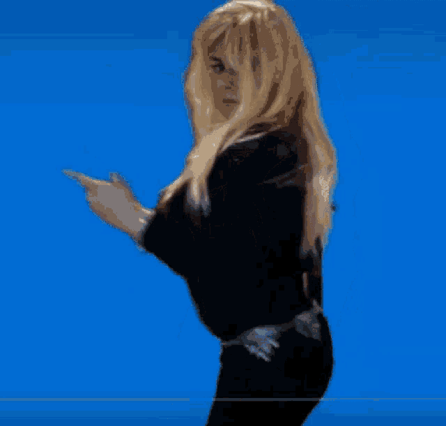 a woman with blonde hair is wearing a black sweater and black pants