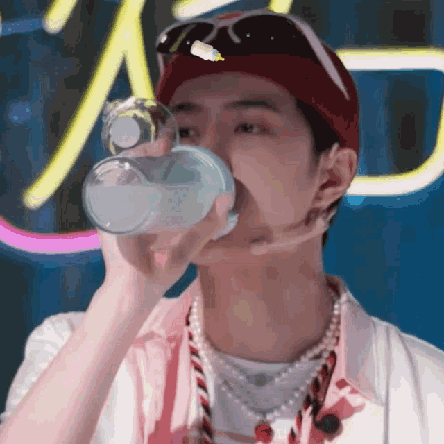 a man wearing sunglasses and a red hat drinks from a bottle