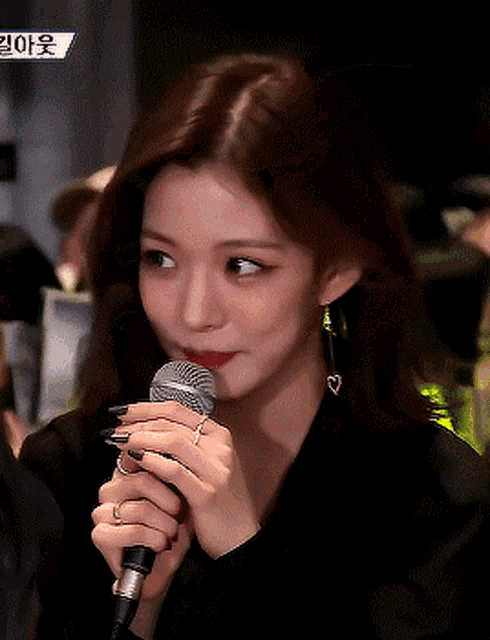 a close up of a woman holding a microphone with a blue sign in the background that says ' korean '