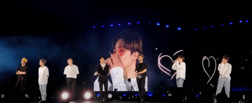 a group of people are standing on a stage in front of a screen with a picture of a man on it .