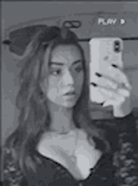 a black and white photo of a woman taking a selfie with her cell phone .