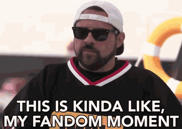 a man with a beard wearing sunglasses and a baseball cap says this is kinda like my fandom moment