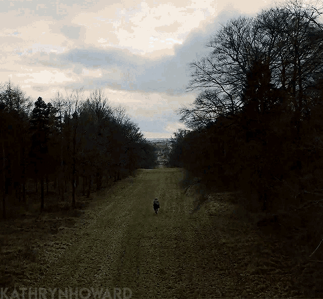 a person walking a dog down a dirt road with kathrynhoward written on the bottom