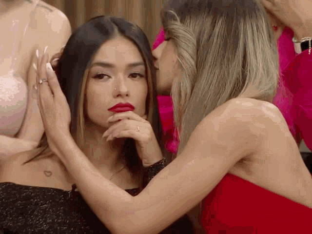 a woman in a red dress kisses another woman 's cheek