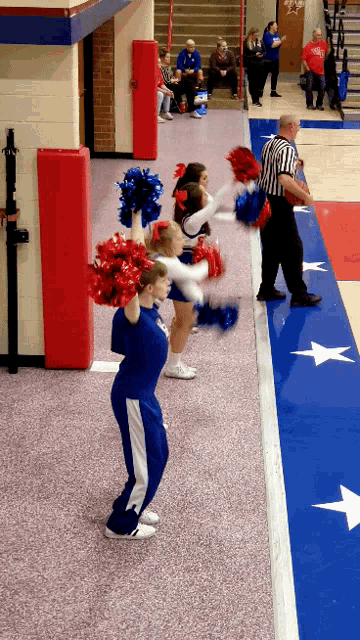 a group of cheerleaders on a basketball court with a referee in the background