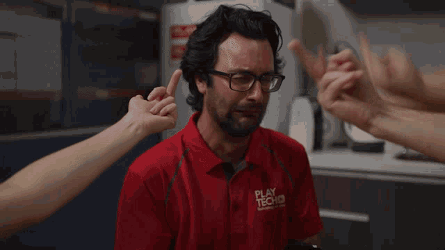 a man in a red shirt is surrounded by people giving thumbs up