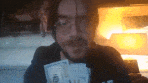 a man wearing glasses is holding a stack of money