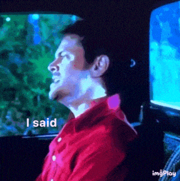 a man in a red shirt is sitting in a car with his eyes closed and says i said .