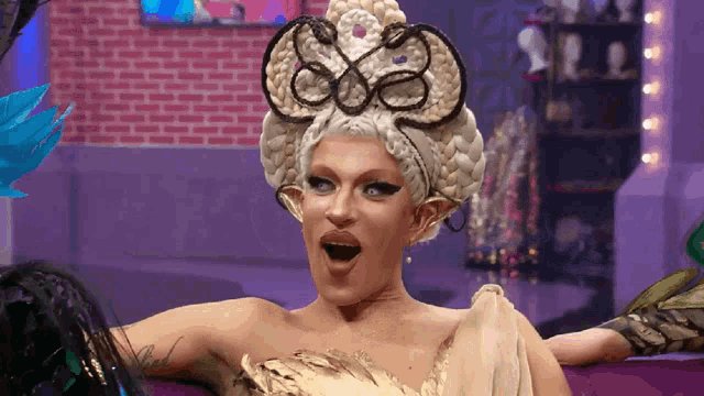 a drag queen is wearing a white wig with a butterfly on it
