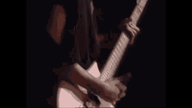 a man is playing a guitar on a stage in the dark .