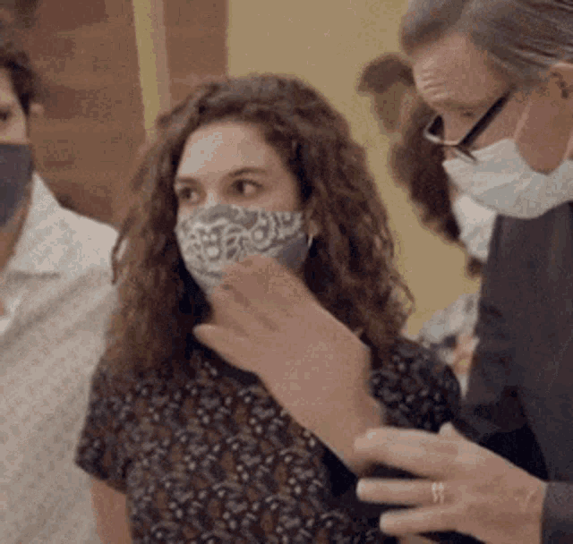 a woman wearing a mask is talking to a man wearing a mask .