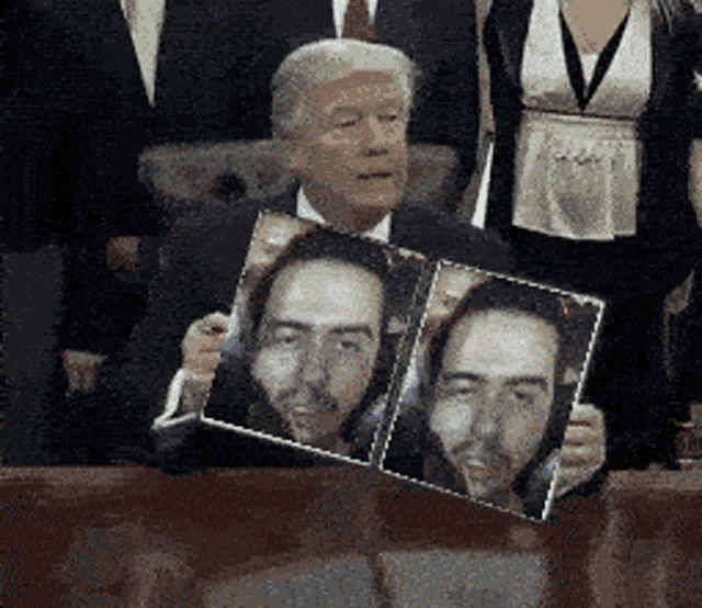 a man in a suit and tie is holding a picture of himself