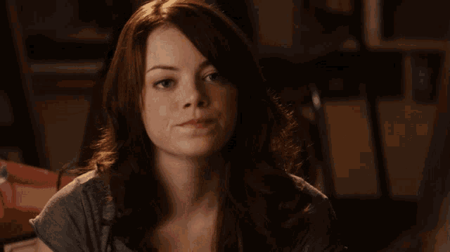 a woman with red hair is wearing a grey shirt and looking at the camera
