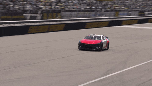 a red and white toyota race car is driving down a road