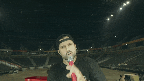 a man wearing a black shirt that says open stands in an empty stadium