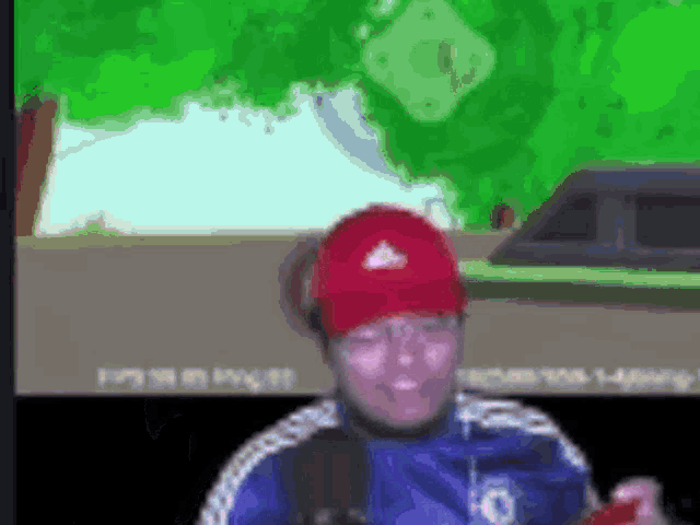 a man wearing a red hat and a blue shirt is playing a video game on a computer .
