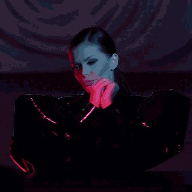 a woman wearing a black jacket with a red light behind her