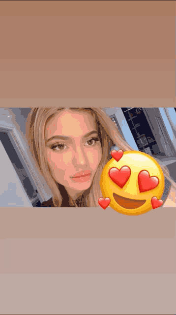 a woman taking a selfie with a smiley face with hearts in her eyes .