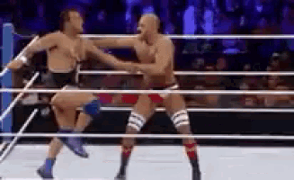 two men are wrestling in a ring and one is kicking the other in the face .