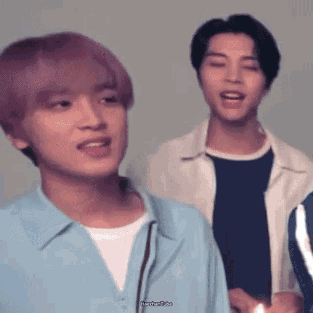 a man with purple hair is standing next to another man .