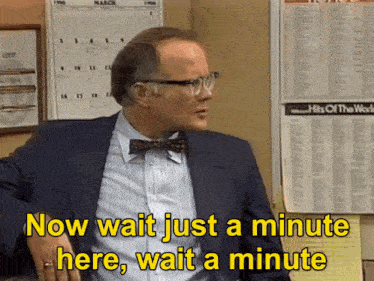 a man wearing glasses and a bow tie says now wait just a minute here wait a minute