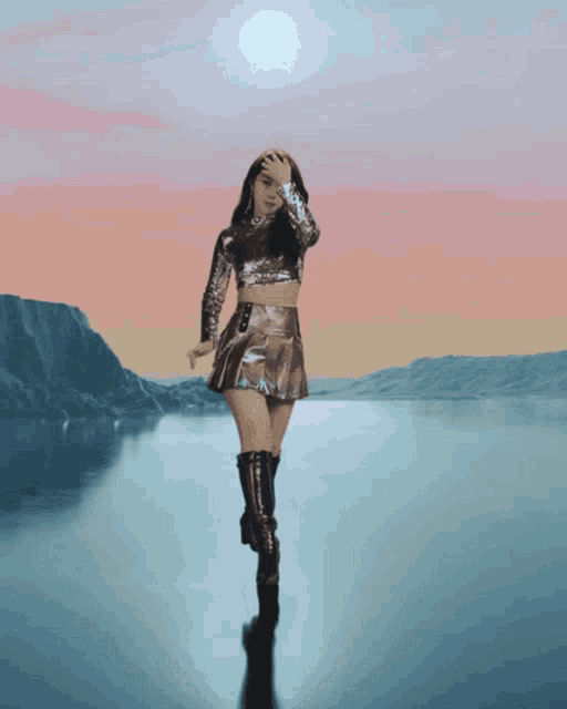 a woman in a sequined top and skirt is walking in front of a lake