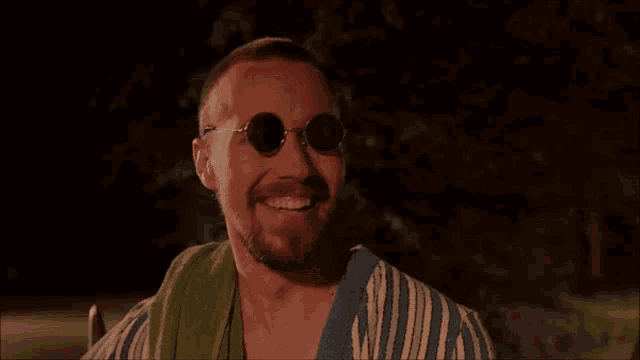 a man wearing sunglasses and a towel has the word mich written on his face